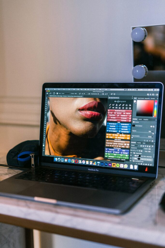 About Us A laptop displaying a graphic design software interface in a creative workspace.